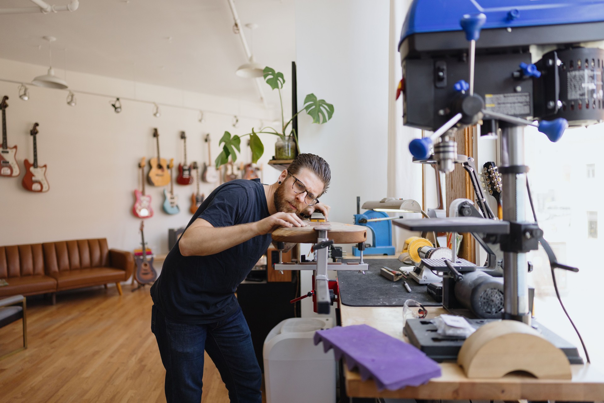 Luthier carefully working on electric guitar body in his workshop